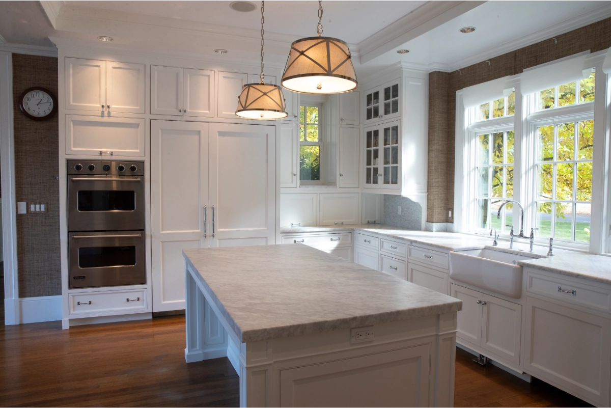 White painted kitchen with built-in cabinets, a central island, and a marble-look countertop.